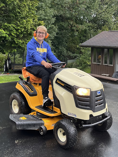 Senior Jack Wonderling posing on his lawnmower. 