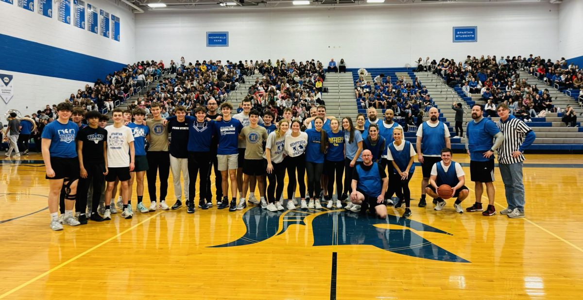 Students and staff basketball players pose together at the conclusion of the game.
