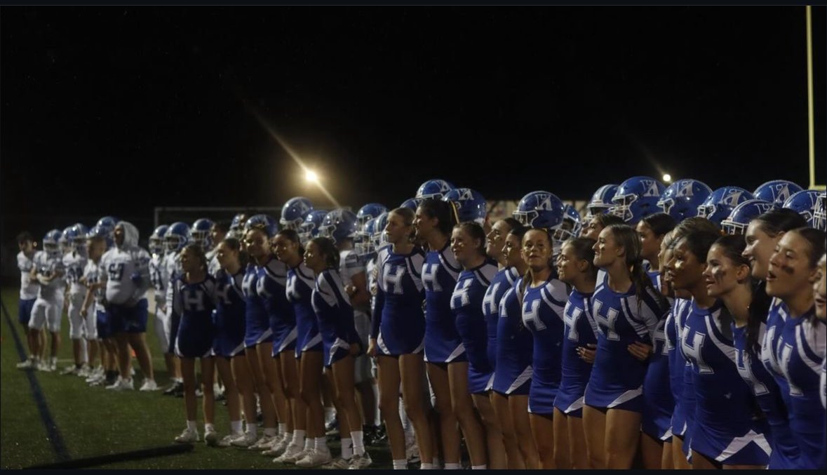 The cheerleaders and football players singing the Alma Mater